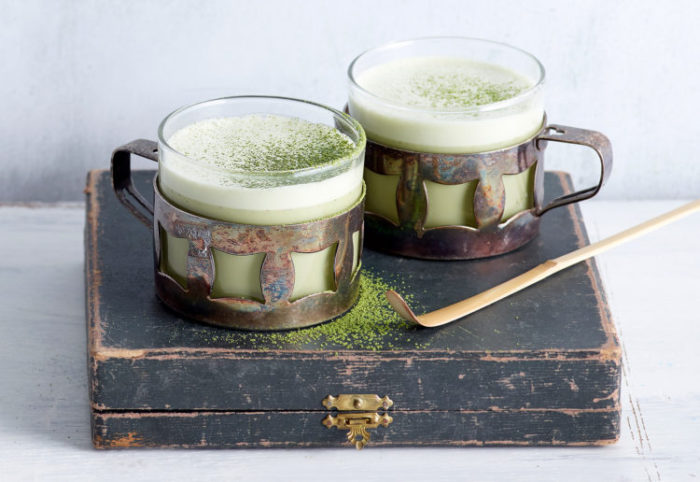 Matcha latte in metalen + glazen mok op oude houten kist met bamboe lepel